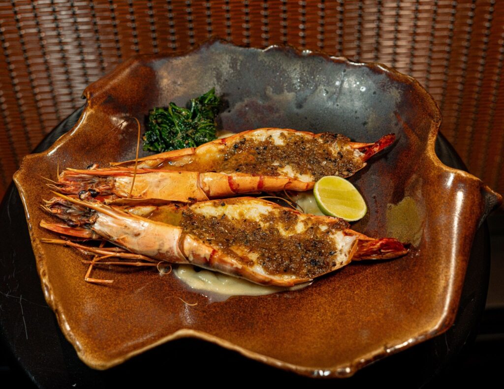 Robatayaki grilled shrimp served with lime and greens on a ceramic plate