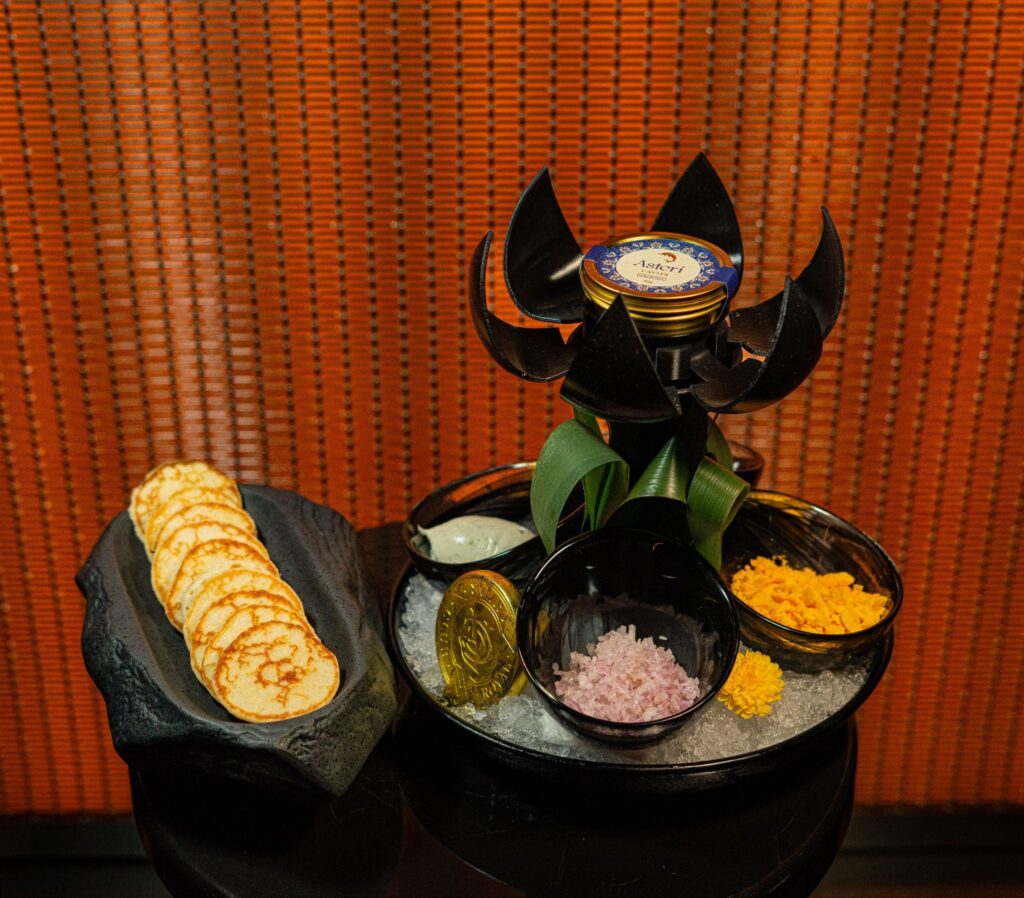 Premium Oscietra caviar served with blinis, crème fraîche, chopped shallots, and traditional garnishes at a luxury restaurant in Dubai