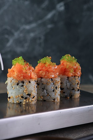 Premium sushi rolls topped with spicy salmon tartare and salmon roe, served at a fine dining restaurant in Dubai