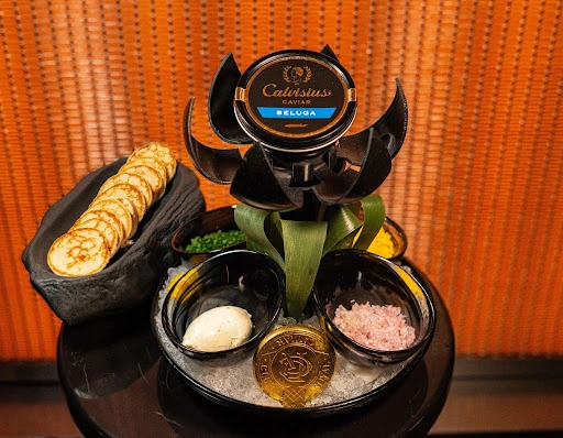 Premium Beluga caviar platter with traditional accompaniments including blinis, crème fraîche, chives, and shallots in Dubai