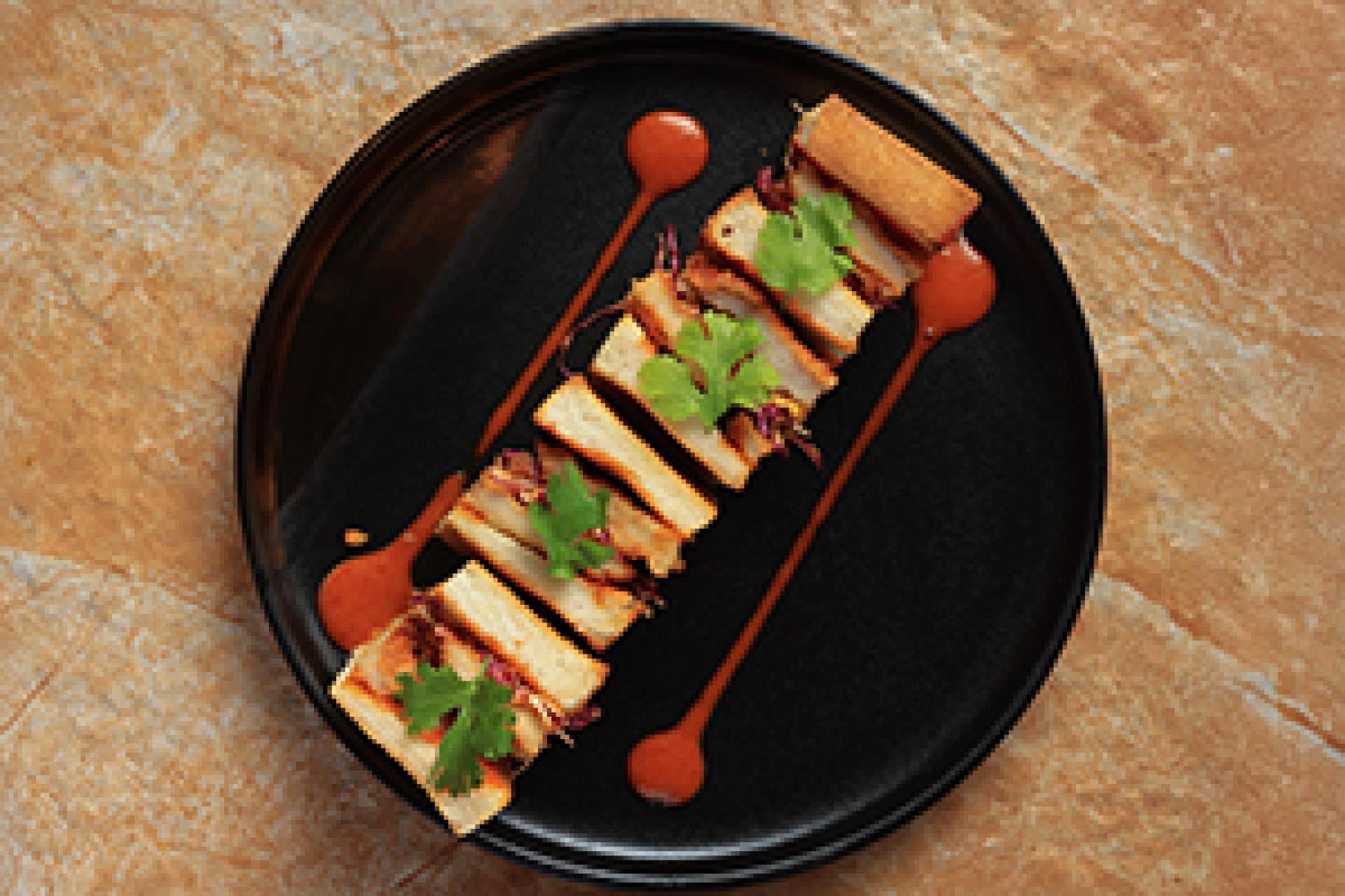 Grilled paneer skewers garnished with fresh herbs and served with signature sauce on a black plate.