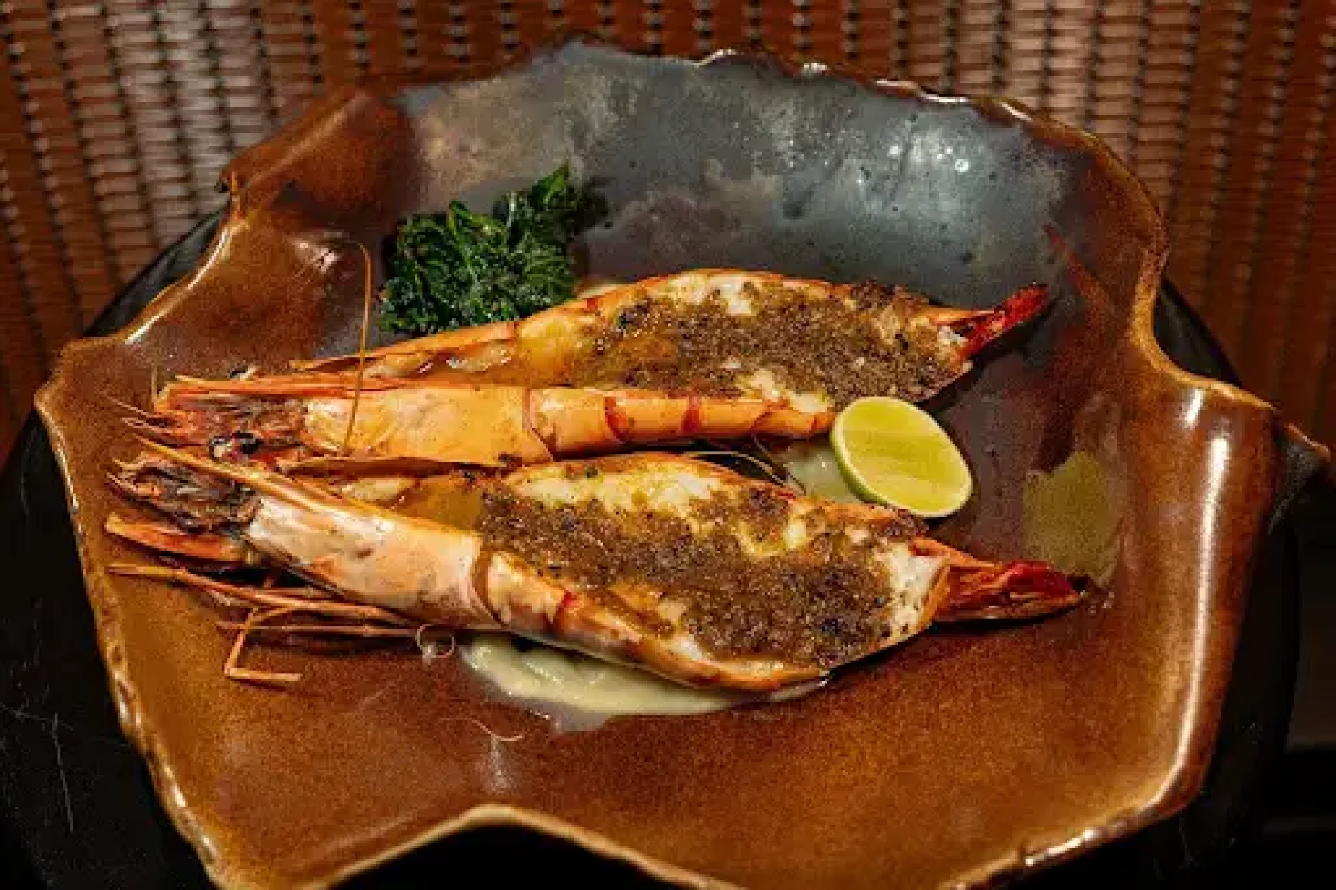 Robatayaki grilled shrimp served with lime and greens on a ceramic plate