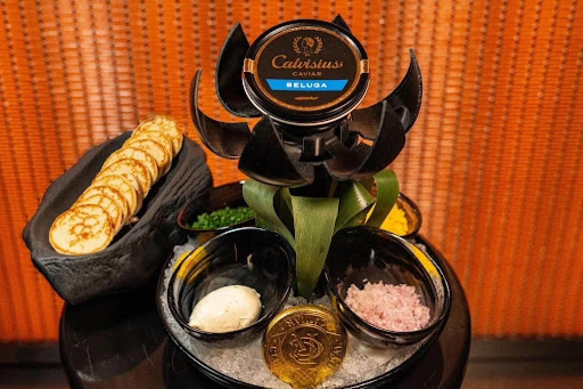 Premium Beluga caviar platter with traditional accompaniments including blinis, crème fraîche, chives, and shallots in Dubai